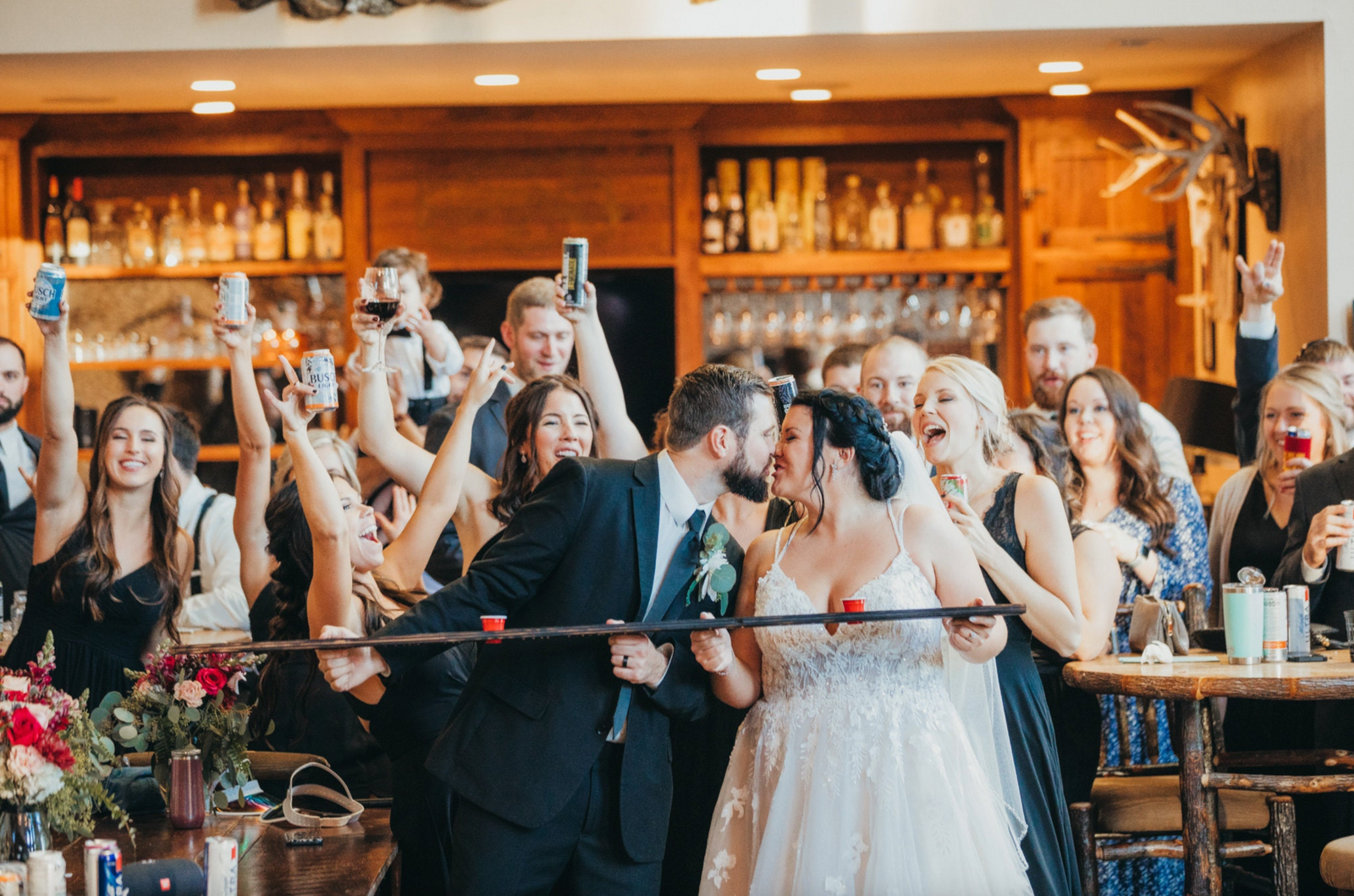bride and groom holding a shot ski with friends around them