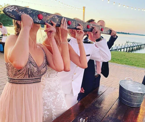 wedding couple drinking from shot ski with friends