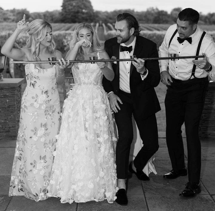 bride, groom and friends drinking from a shot ski